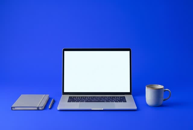 A laptop, notebook and coffee mug